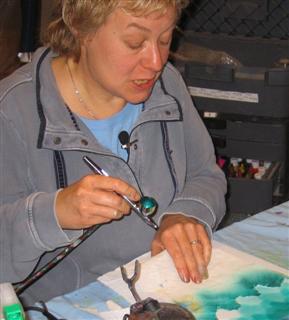 Airbrushing her work using torn tissue to create a pattern
